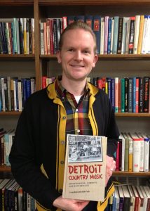 Craig Maki holds his book "Detroit Country Music: Mountaineers, Cowboys, and Rockabillies" at the U of M Press archive. Photo by Keith Cady